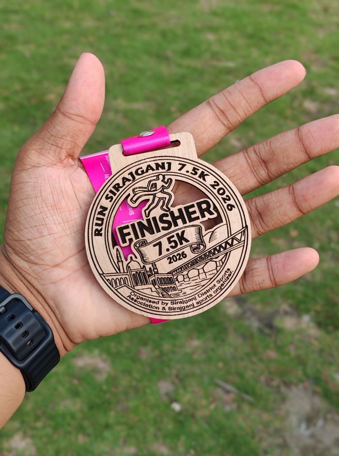 A hand holding a 7.5K finisher medal from the Run Sirajganj race.