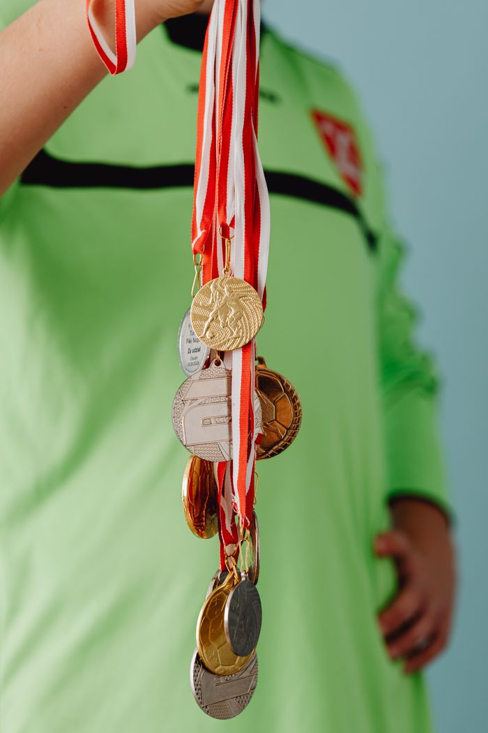 Teen athlete proudly displaying a collection of sports medals in a close-up shot.